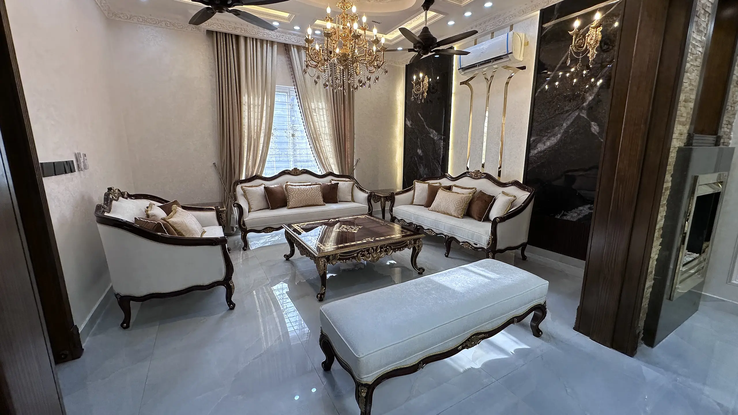 Luxurious classic drawing room with a white and gold sofa set and glass coffee table.