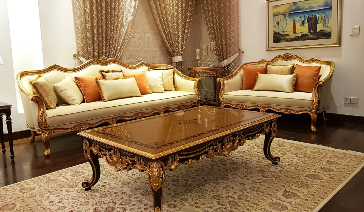 Ornate classic drawing room with intricately carved, gold-finished sofas and a detailed coffee table.