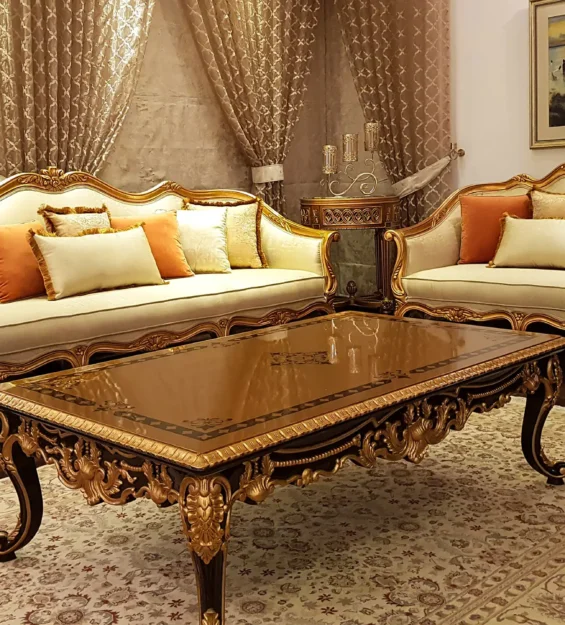 Ornate classic drawing room with intricately carved, gold-finished sofas and a detailed coffee table.