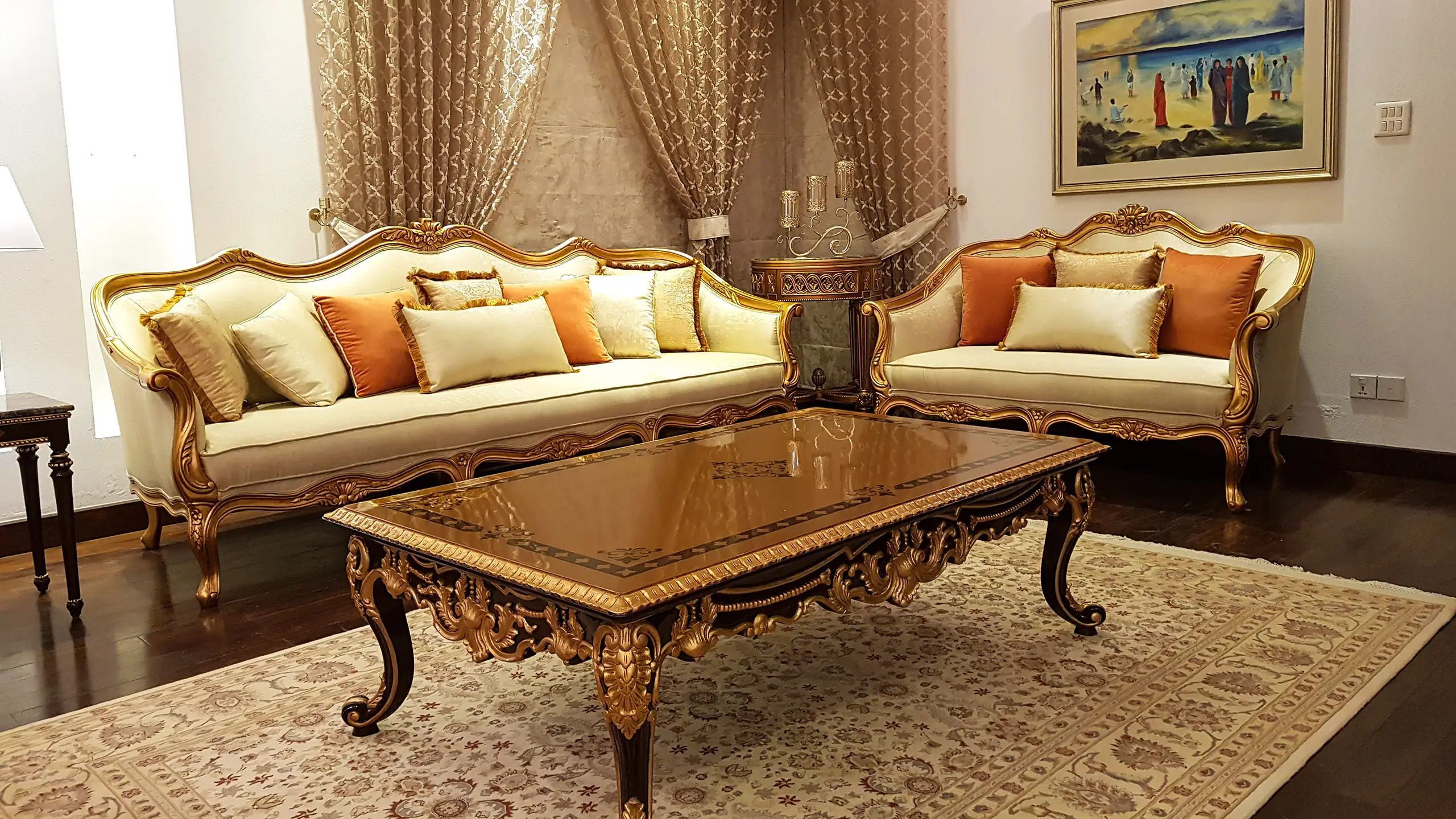 Ornate classic drawing room with intricately carved, gold-finished sofas and a detailed coffee table.