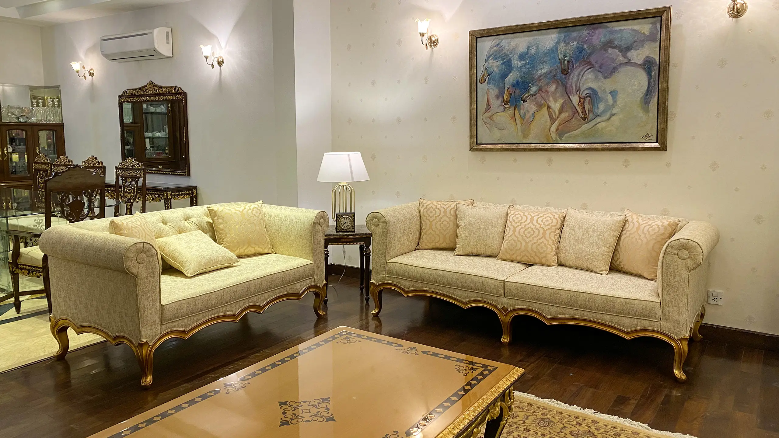Traditional drawing room featuring beige sofas, classic furniture, and a large horse painting.