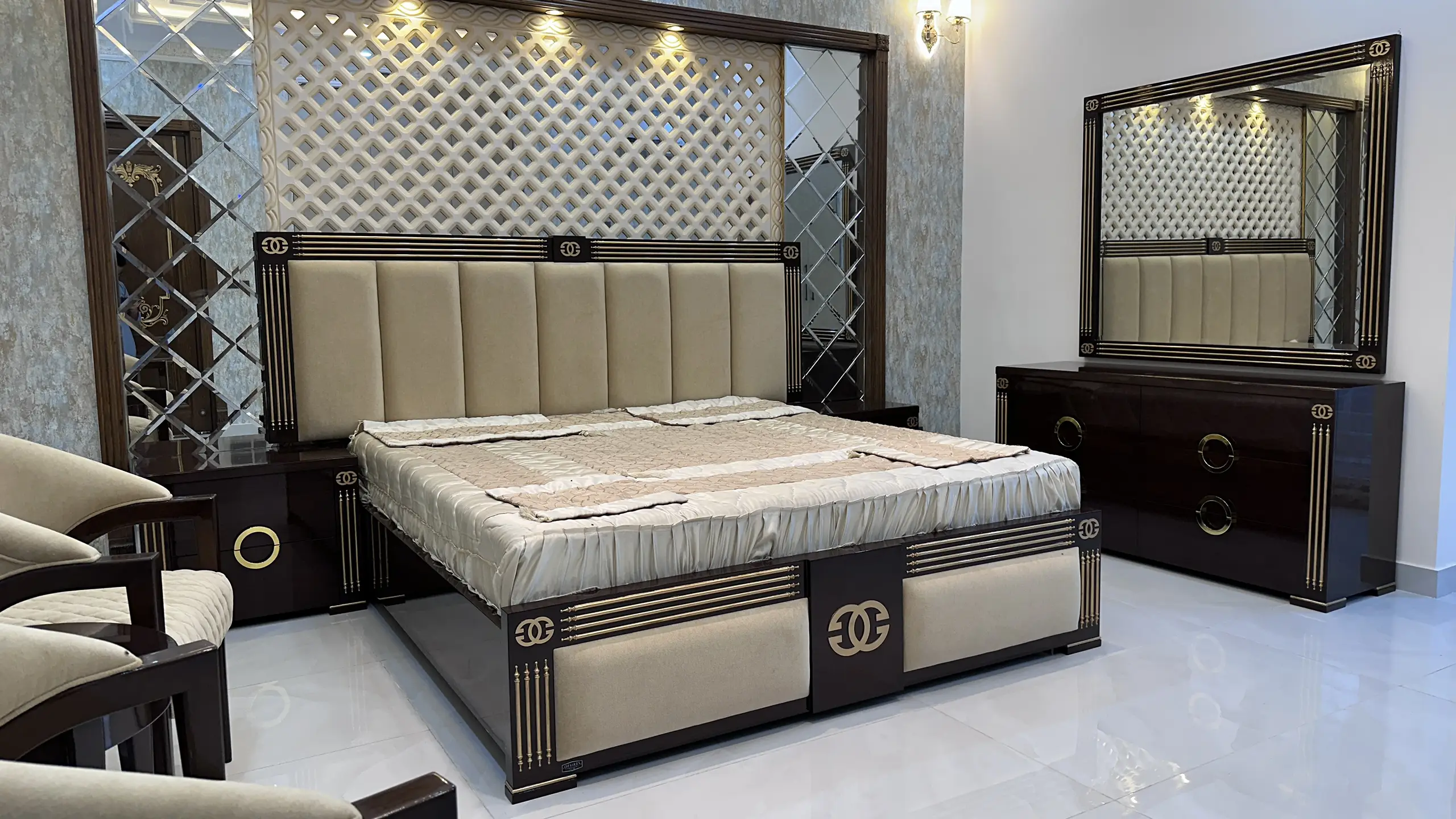 Modern bedroom showcasing a large upholstered bed, dark wood furniture, and mirrored wall accents.