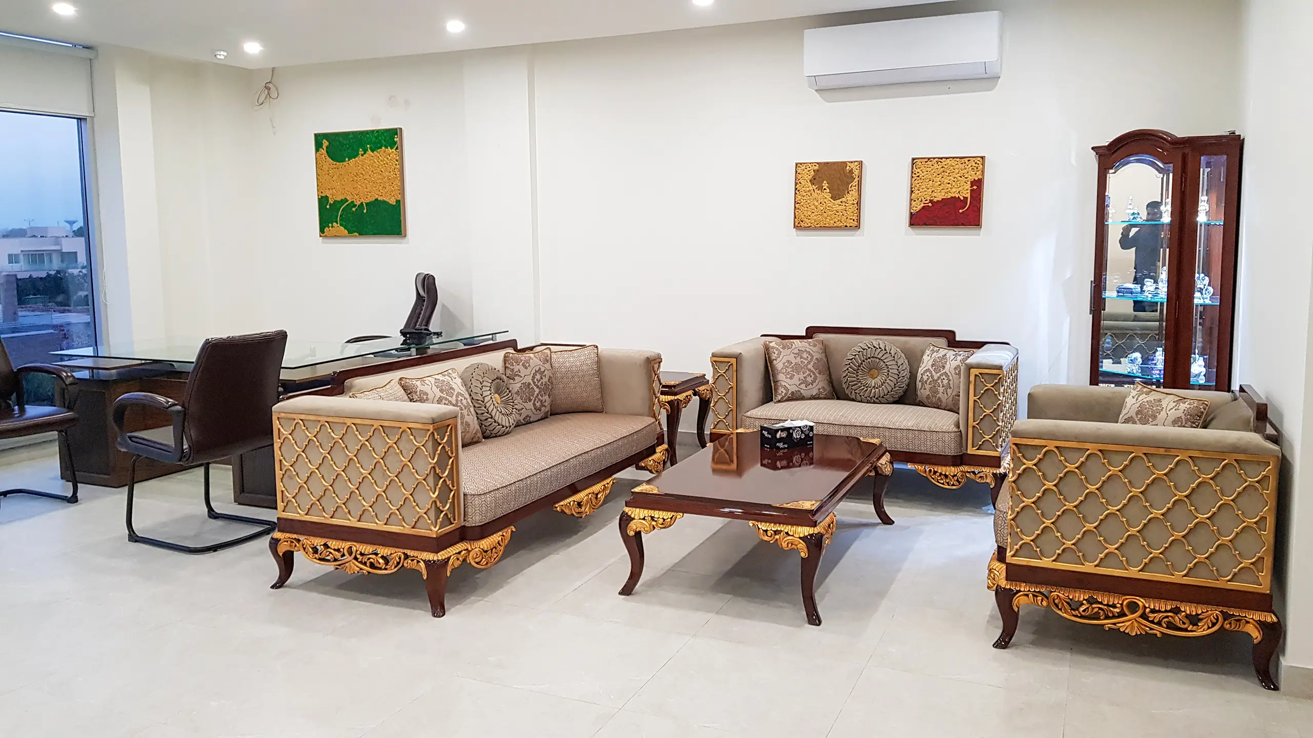 Classic carved wooden sofa set and executive desk in a formal office space.