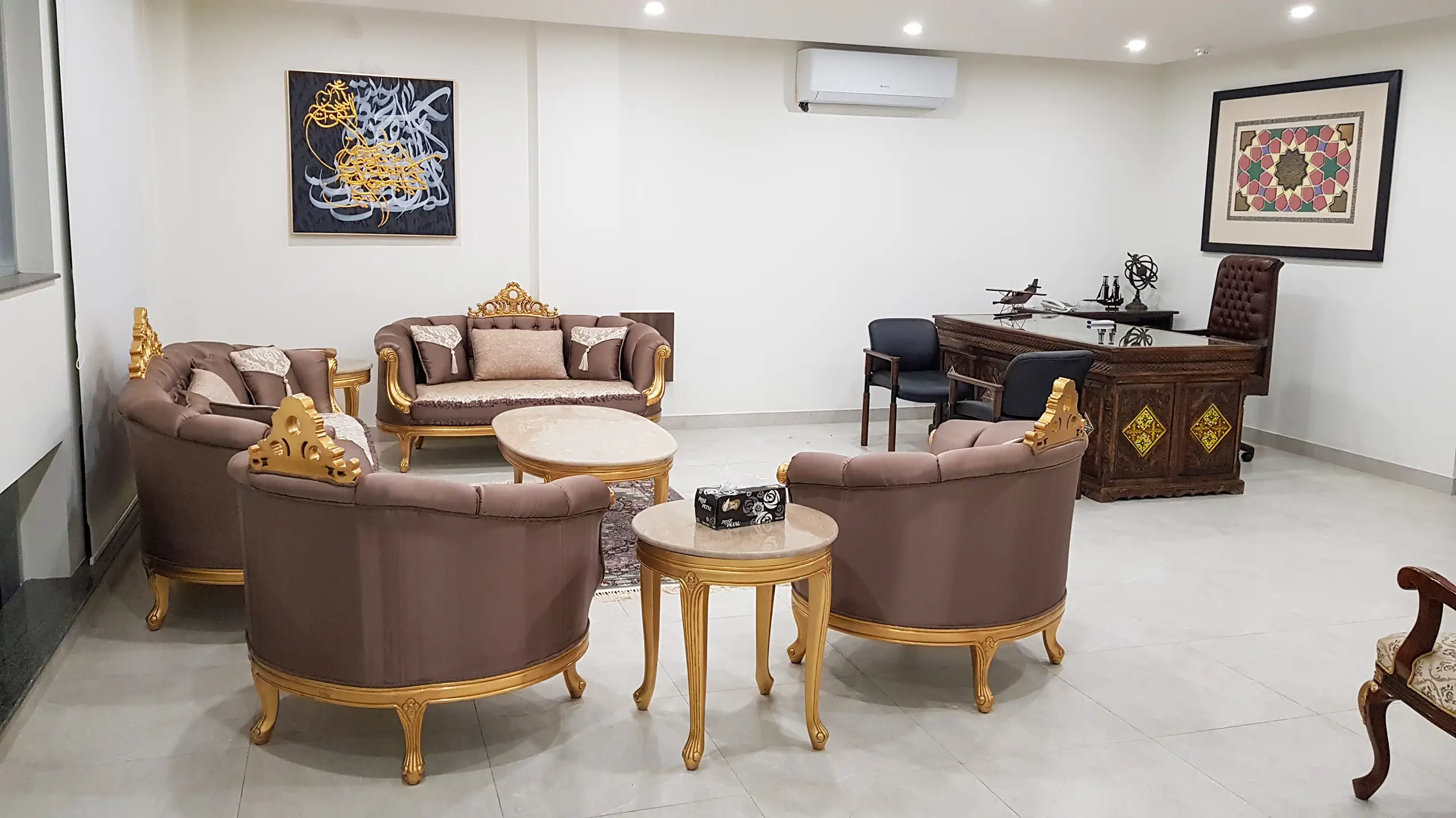 Executive office featuring a classic carved desk and a traditional gold-accented sofa set.