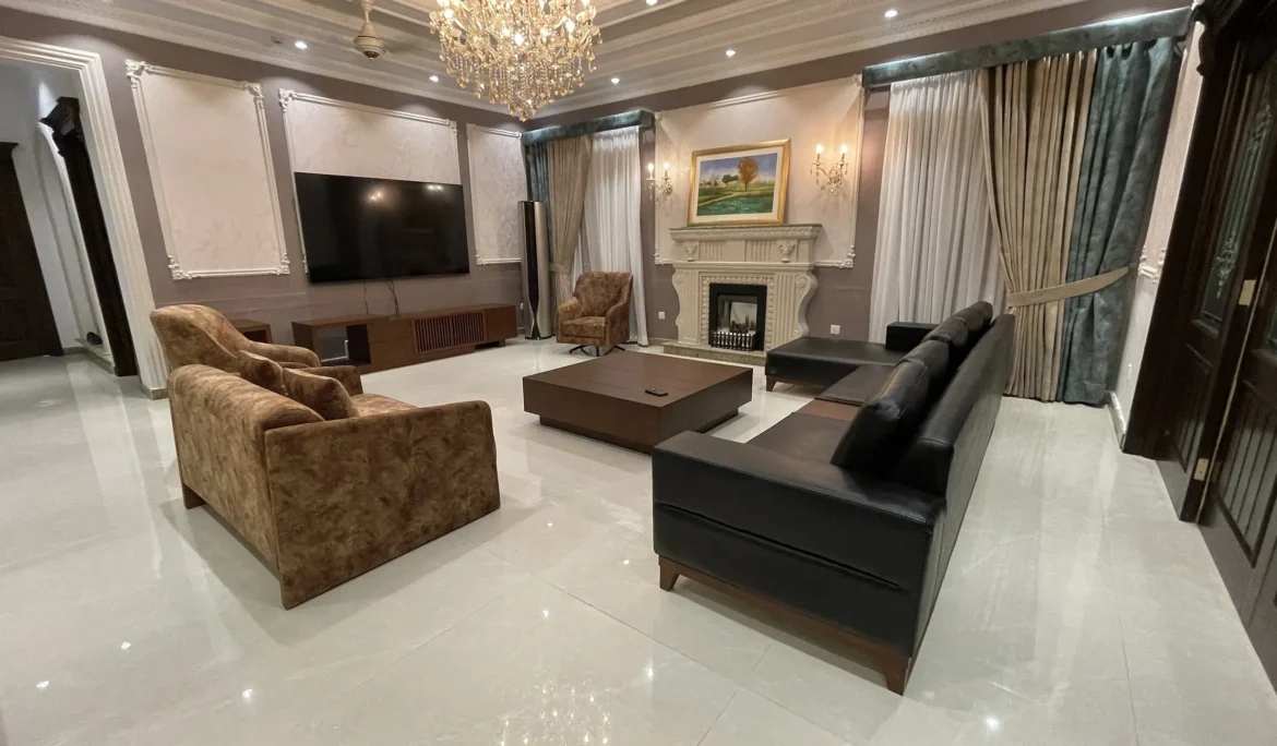 Wide view of an elegant living room with a fireplace, a black sofa, and brown armchairs.