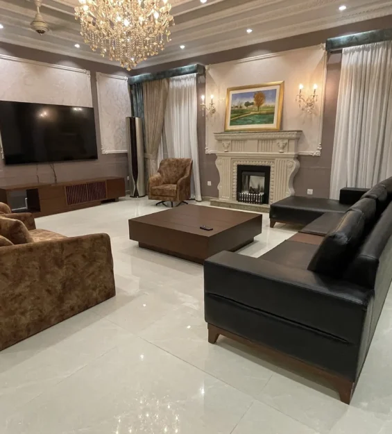 Wide view of an elegant living room with a fireplace, a black sofa, and brown armchairs.