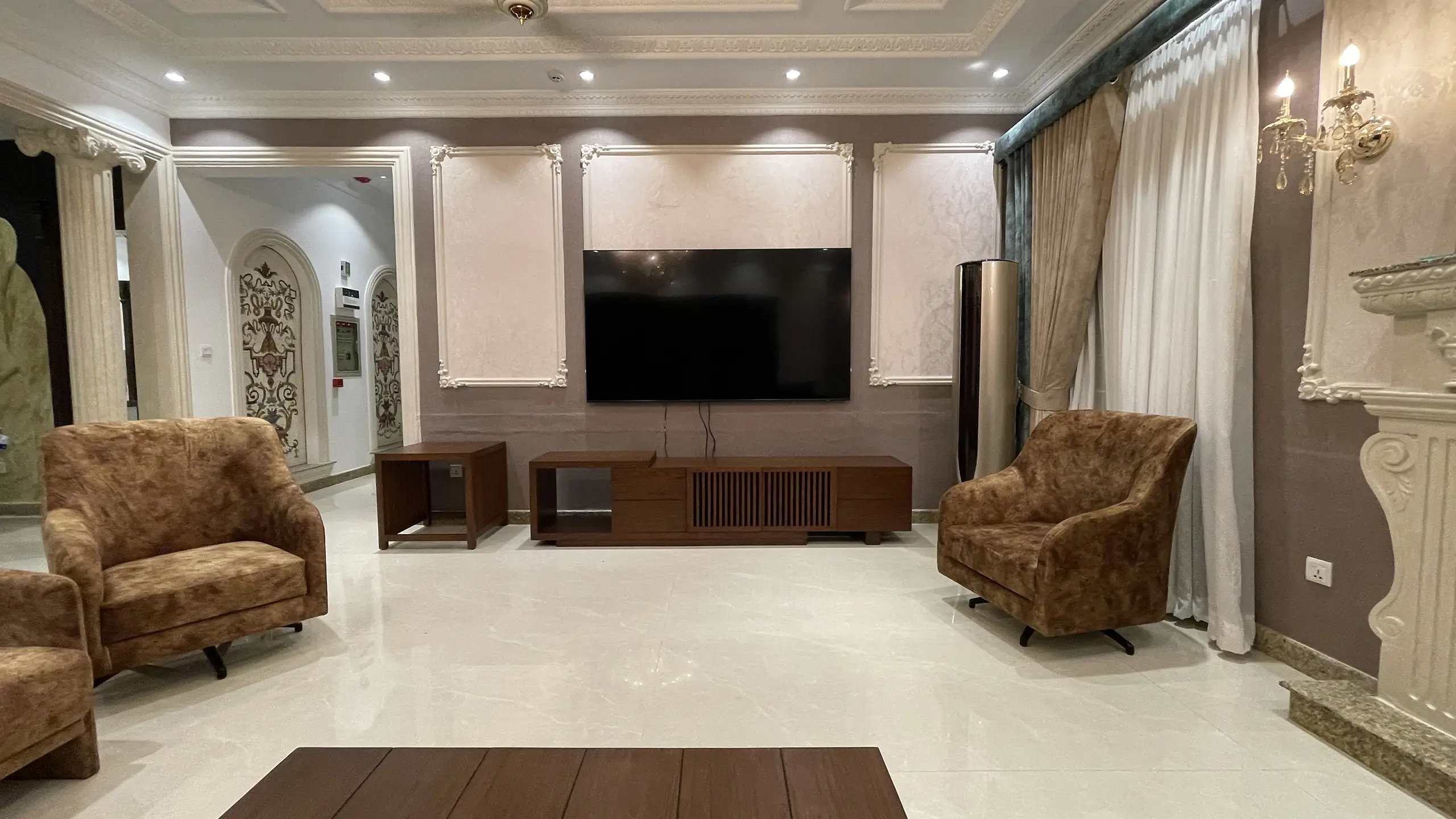 Modern media room with brown swivel armchairs and a minimalist wooden TV console.