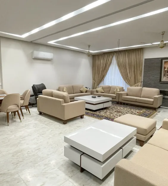 Spacious open-plan living and dining area with contemporary beige sofas and white coffee tables.