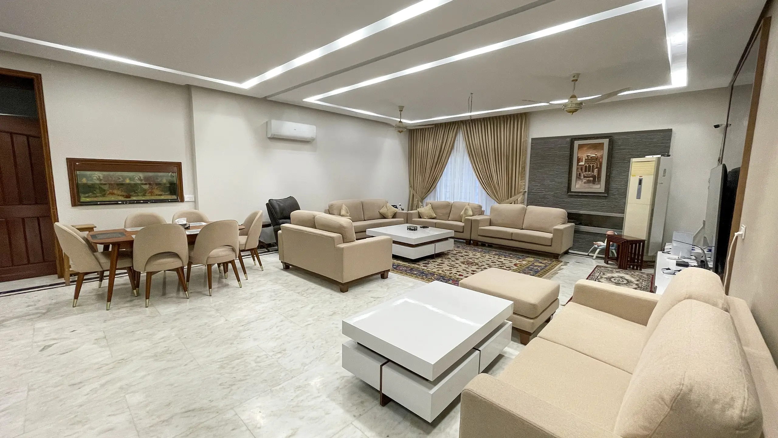 Spacious open-plan living and dining area with contemporary beige sofas and white coffee tables.