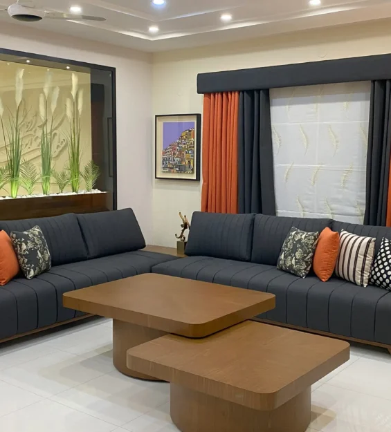 Contemporary living room featuring a large grey L-shaped sofa, modern coffee tables, and a large indoor planter.