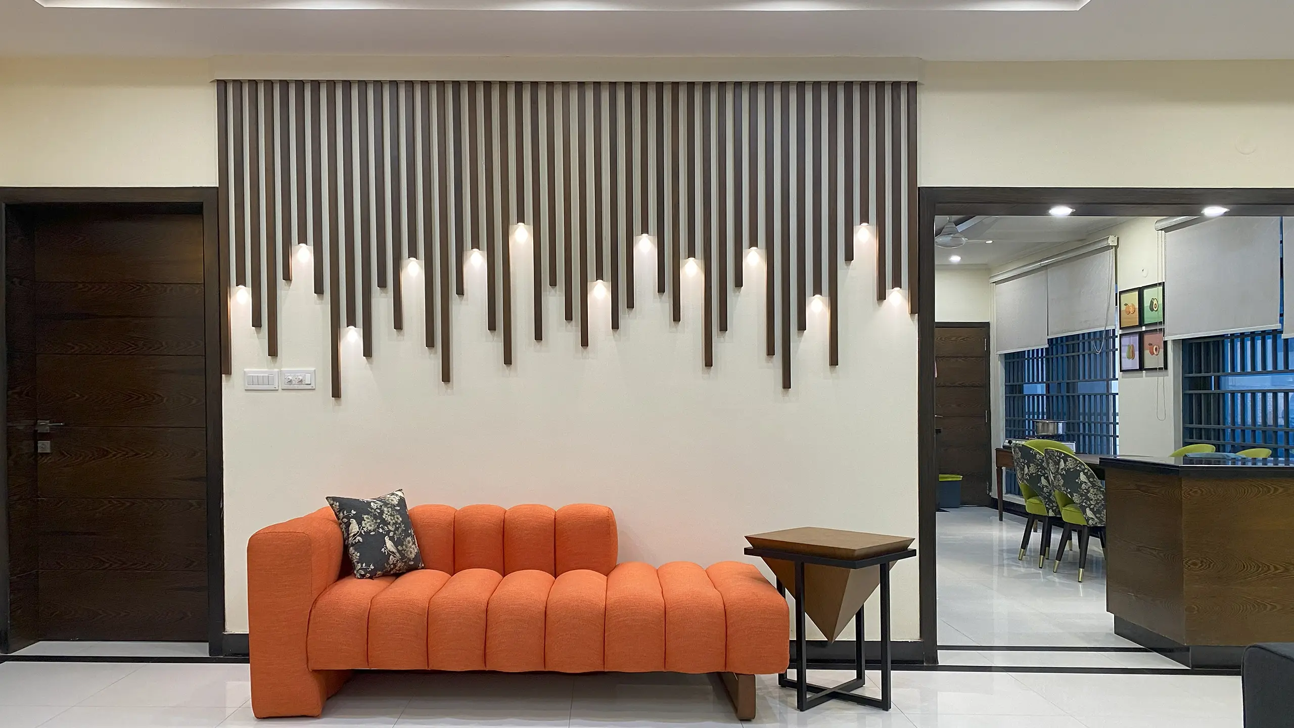 Modern entryway with a bright orange channel-tufted chaise lounge and a creative wall-mounted light fixture.