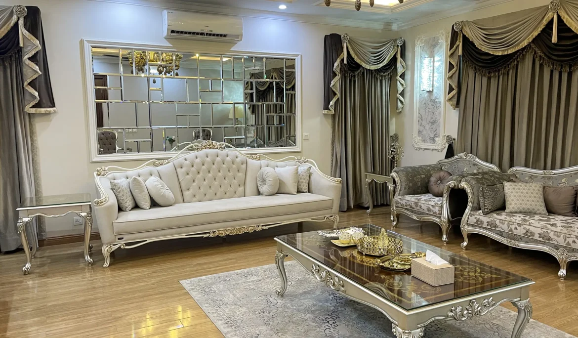 Elegant classic drawing room with a white tufted sofa and a floral upholstered sofa set on a wooden floor.