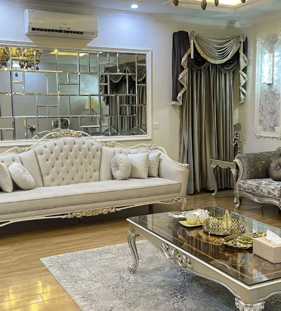 Elegant classic drawing room with a white tufted sofa and a floral upholstered sofa set on a wooden floor.