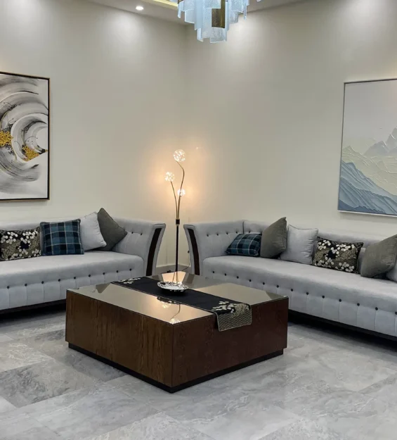 Spacious living room with two light grey sofas, a dark wood coffee table, and large abstract wall art.