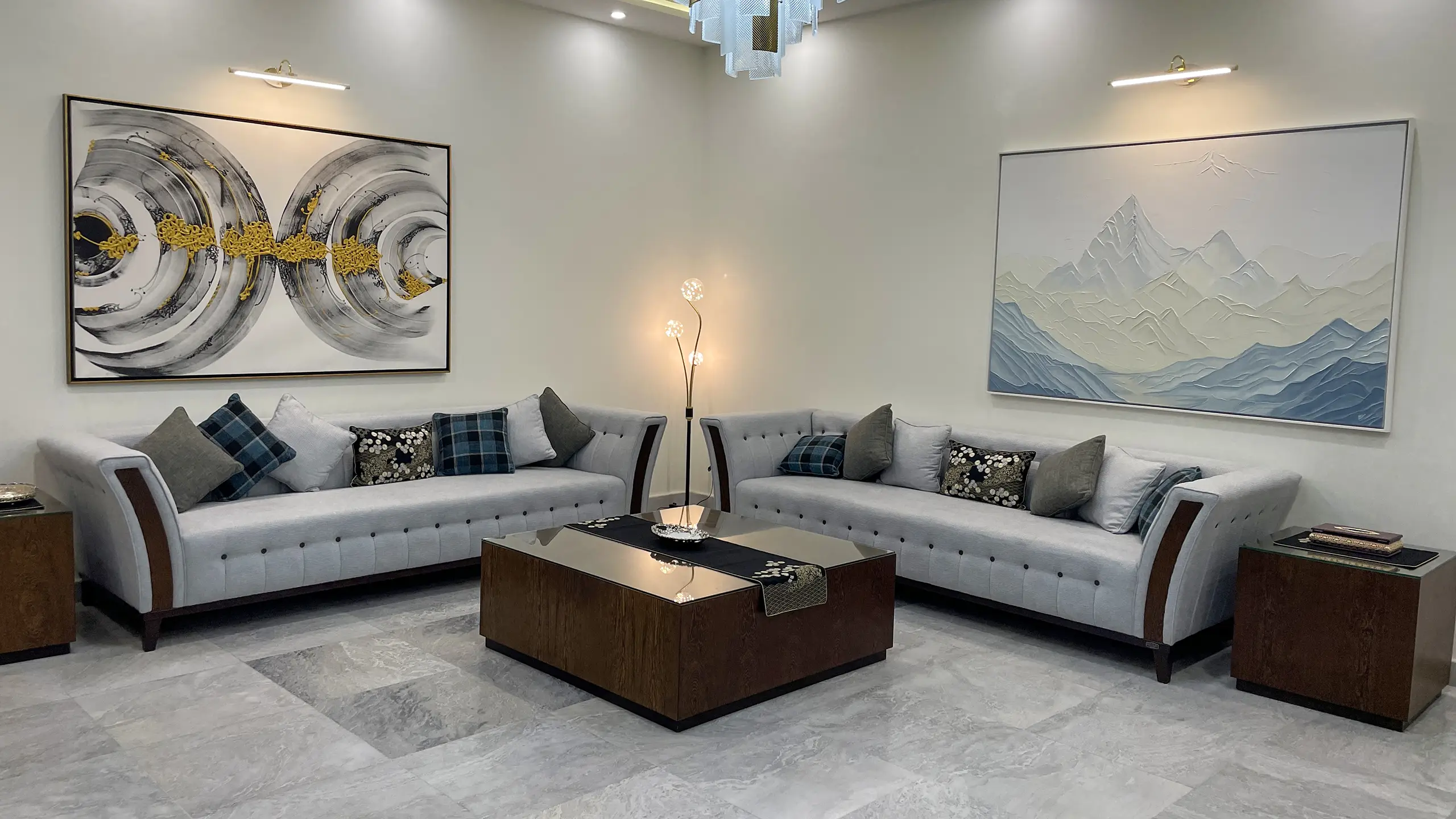 Spacious living room with two light grey sofas, a dark wood coffee table, and large abstract wall art.