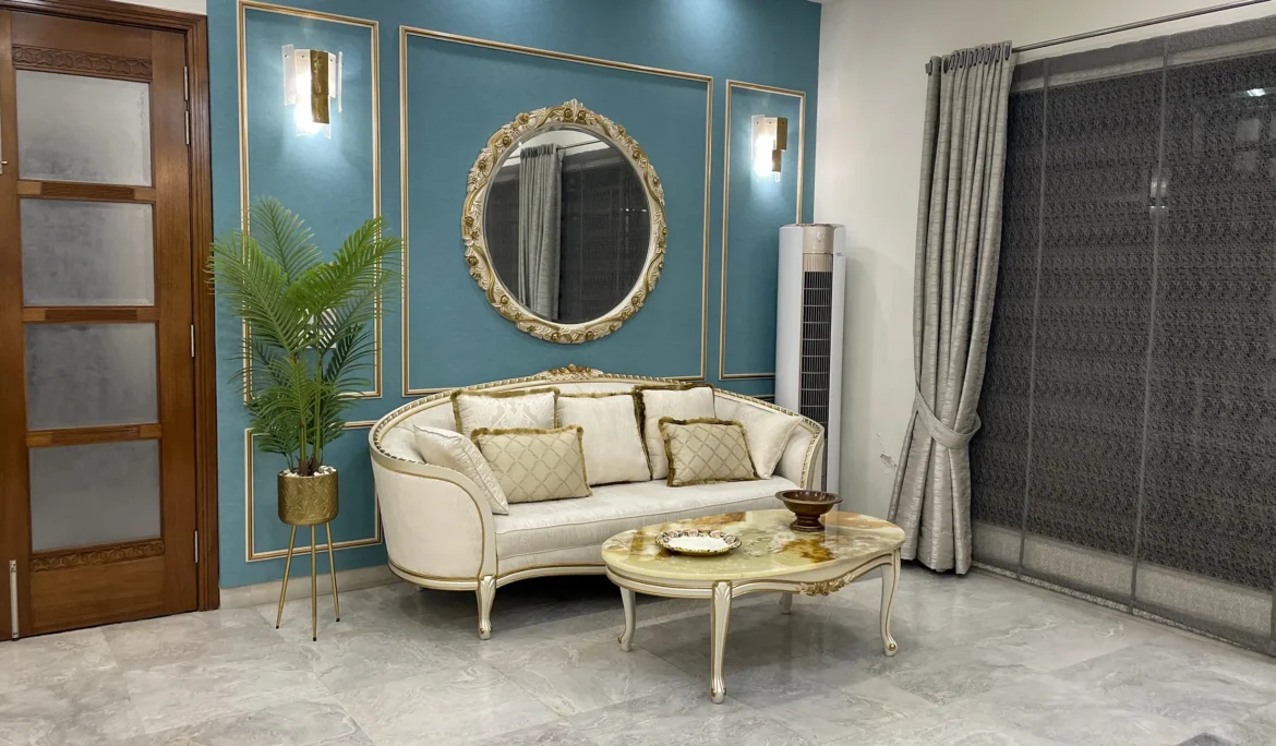 Classic living room with a curved off-white sofa, marble-top coffee table, and an ornate gold mirror on a teal wall.