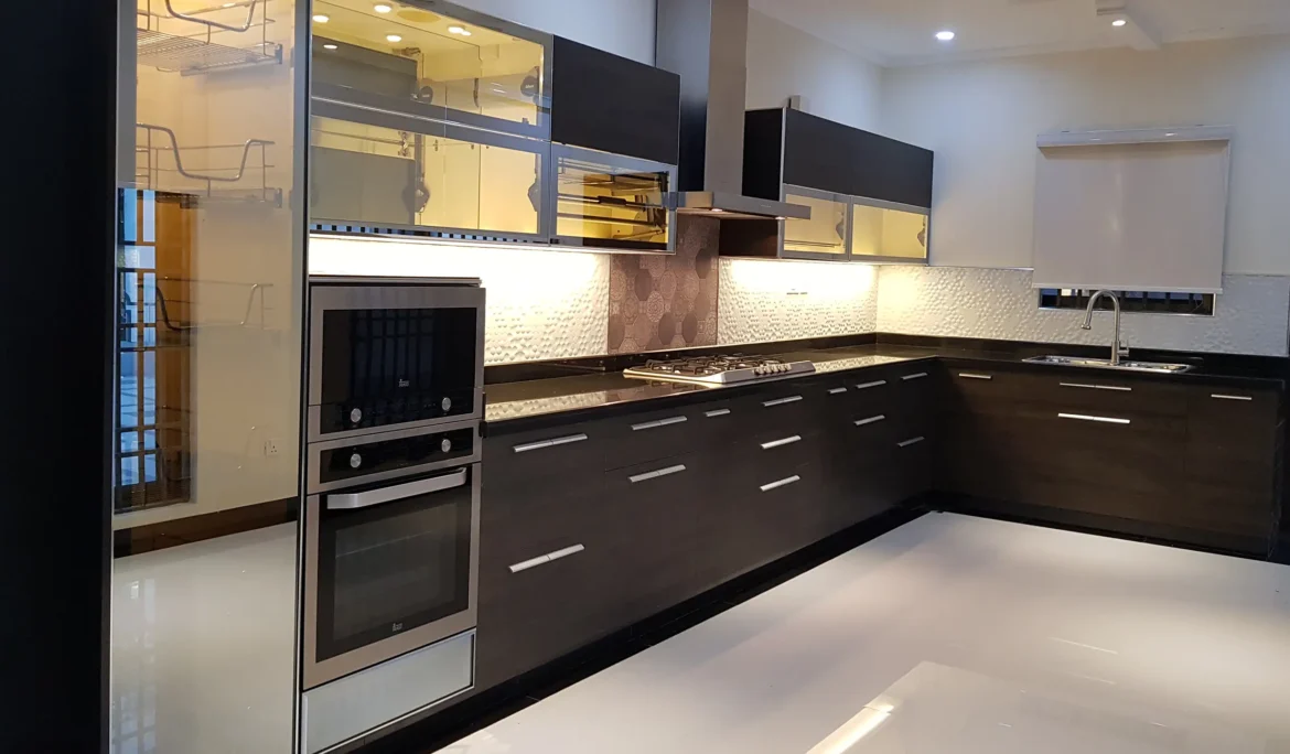 Sleek modern kitchen with dark cabinets, black countertops, and stainless steel appliances.