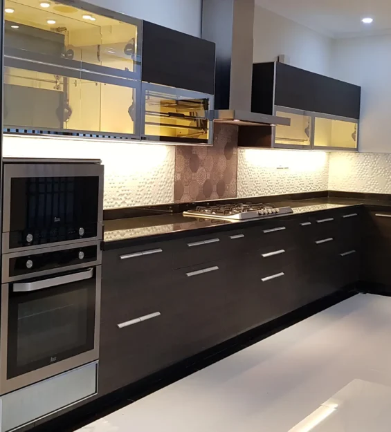 Sleek modern kitchen with dark cabinets, black countertops, and stainless steel appliances.