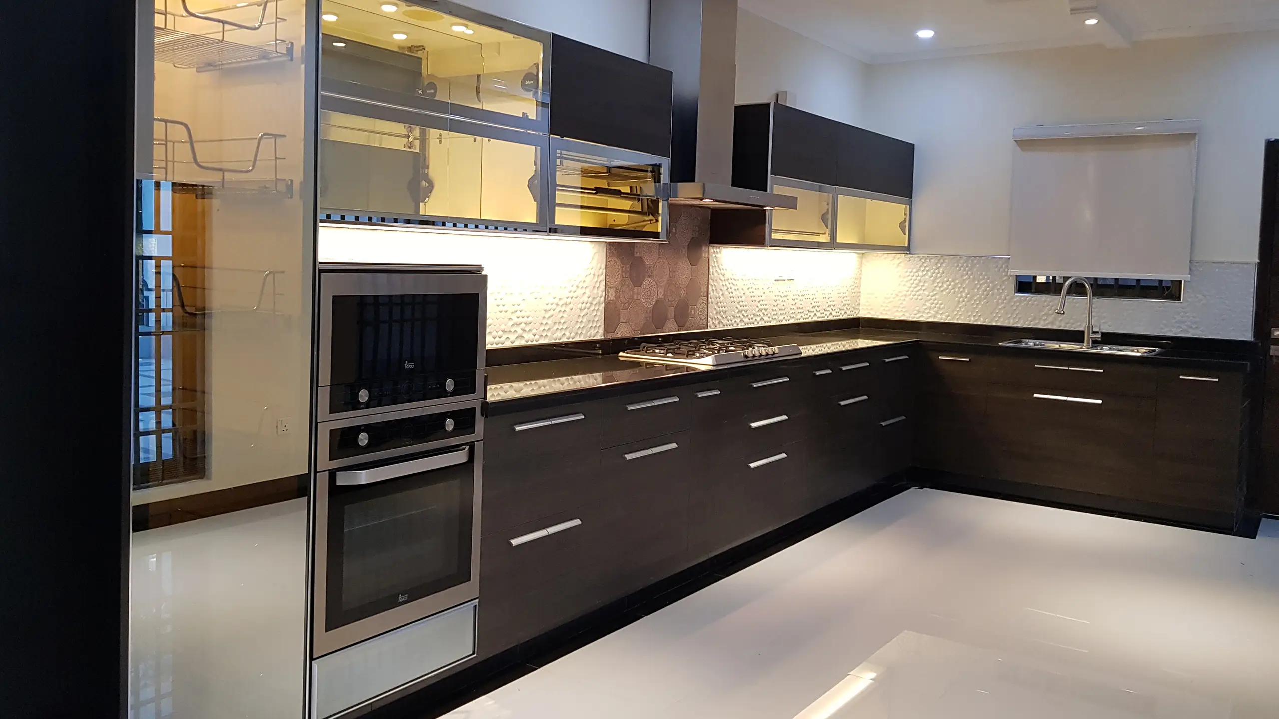 Sleek modern kitchen with dark cabinets, black countertops, and stainless steel appliances.
