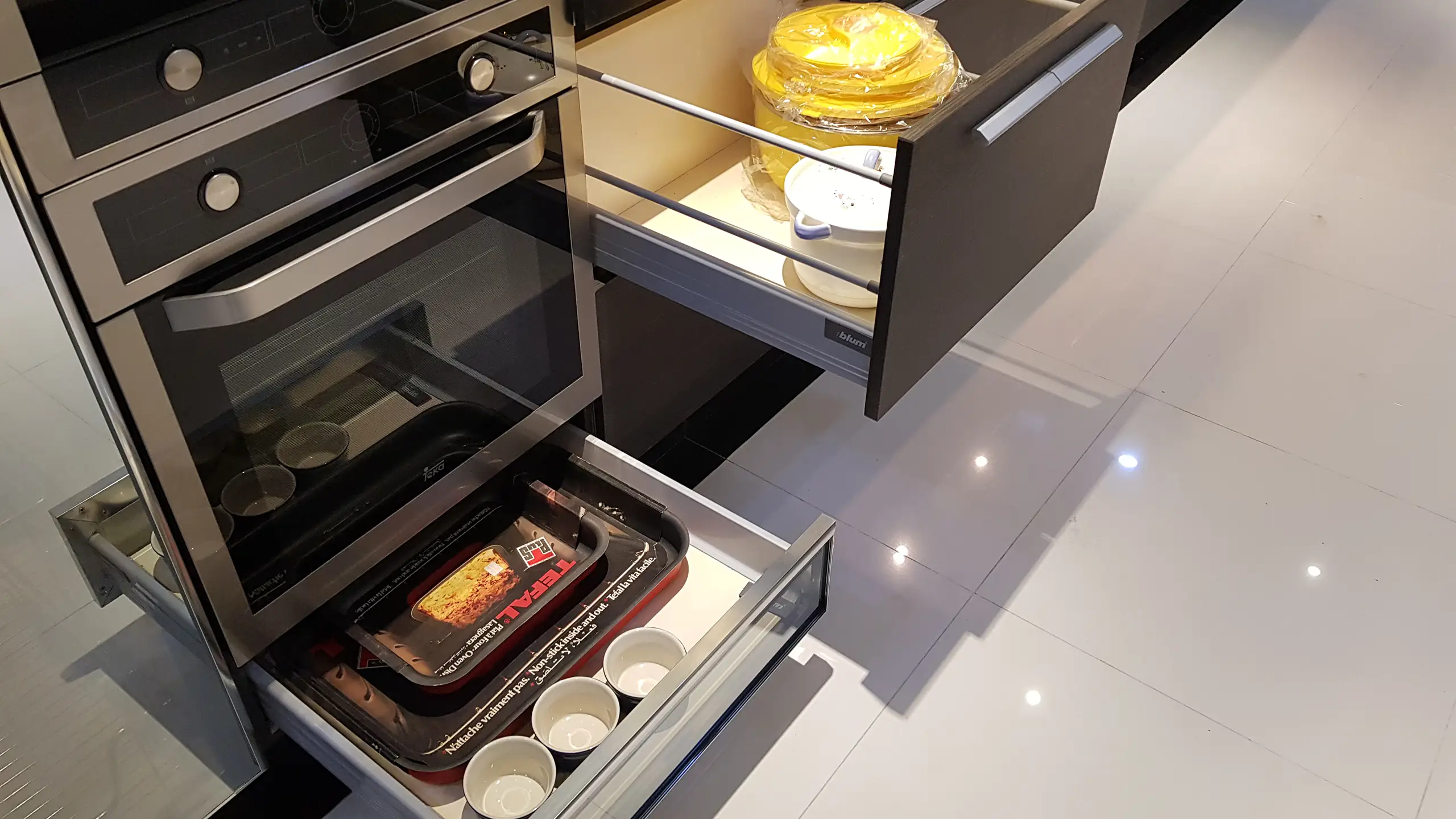 Organized deep drawers in a modern kitchen for storing baking trays and kitchenware.
