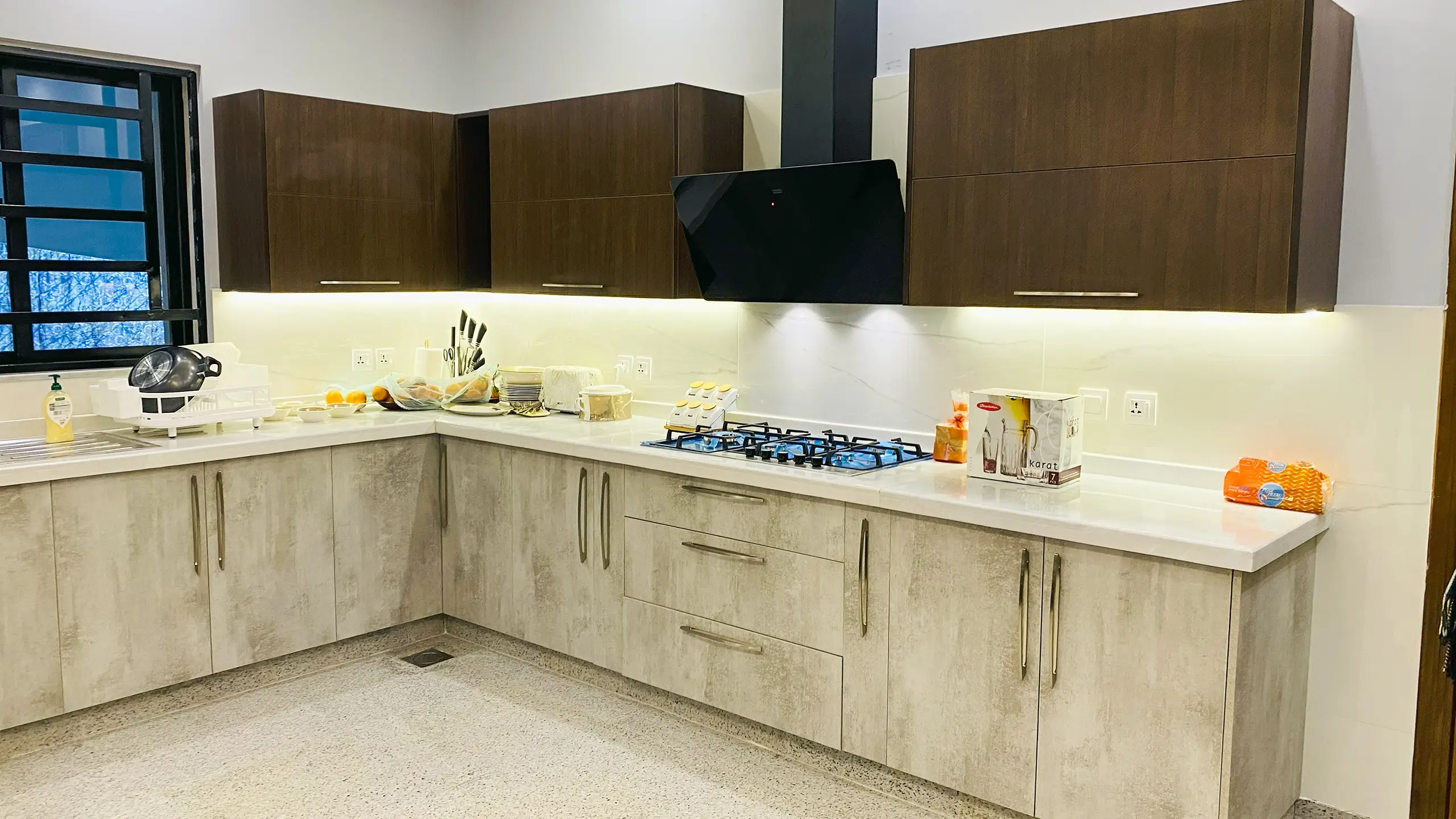 Two-tone modern kitchen with light wood-texture lower cabinets and dark upper cabinets.